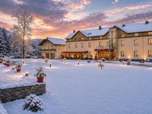 a large building in the snow with the sun setting at Carré Py' Hôtel in Bagnères-de-Bigorre