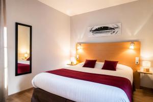 a hotel room with a large bed and a mirror at Carré Py' Hôtel in Bagnères-de-Bigorre
