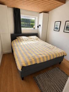 a bedroom with a bed with a yellow and blue stripes at Krageholmshytten in Karrebæksminde