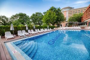 a large swimming pool with chairs and umbrellas at Gladiola 4-star in Golden Sands +16 photos