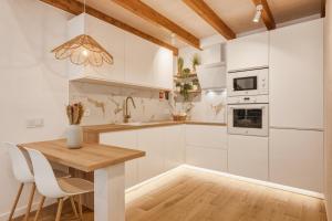 a kitchen with white cabinets and a wooden table at Casinha do Beco in Lagos +3 photos