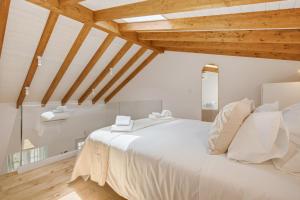 a bedroom with a large white bed with wooden ceilings at Casinha do Beco in Lagos