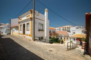a small white building on a street with buildings at Casinha do Beco in Lagos