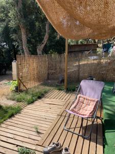 a chair sitting on a wooden deck under an umbrella at Châlet de charme in Taillet