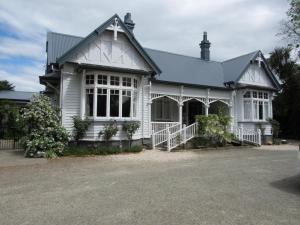 a white house with a gray roof at White Elephant Accomodation in Motueka