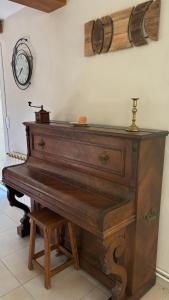 a wooden piano sitting in a room with a clock on the wall at Chez Camille aux Sieges in Les Rives