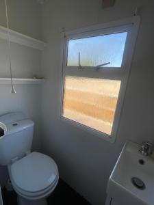 a bathroom with a toilet and a window at Gunthorpe Mobile Home in East Bridgford
