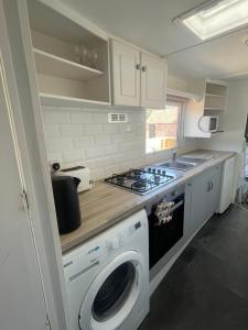 a kitchen with a stove and a washing machine at Gunthorpe Mobile Home in East Bridgford