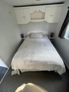 a small bedroom with a bed and white cabinets at Gunthorpe Mobile Home in East Bridgford