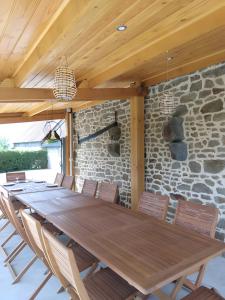 a wooden table and chairs in front of a stone wall at Le gîte de L'Étable in Magny-le-Désert