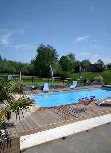 a large swimming pool with a wooden deck and chairs at Le gîte de L'Étable in Magny-le-Désert