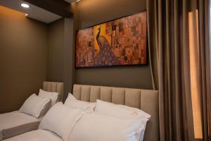 a bedroom with two beds with white pillows and a painting at 2S Vila Boutique Pogradec in Pogradec