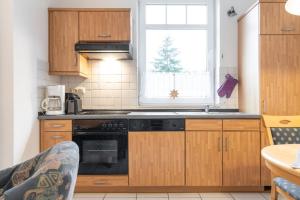 a kitchen with wooden cabinets and a black oven at Haus Roland, Wohnung 03 in Zinnowitz