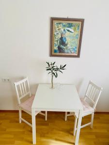 a white dining room table with two chairs and a painting at Dinkelsbühl-Ferienappartement in Mönchsroth +7 photos