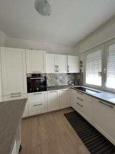 a white kitchen with white cabinets and black appliances at Il Cenerone in Pineto +26 photos