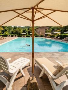 a pool with two lounge chairs and an umbrella at Hotel Residence Sant'Uberto in Roccastrada