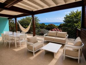a patio with a table and chairs and a view of the ocean at La Baie des Villas in Deshaies