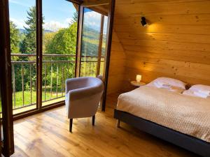a bedroom with a bed and a chair and windows at Domki na Szlaku in Brenna