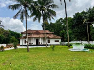 a white house with palm trees in a yard at Haritham Heritage Villa - Rooms in Vadakkāncheri