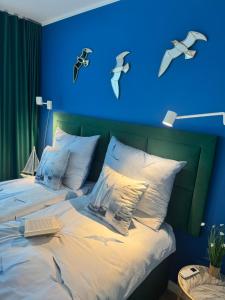 a blue bedroom with a bed with birds on the wall at Zalotna Mewa Gąski in Gąski