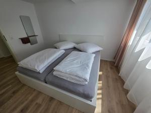 a bed with white sheets and pillows in a room at Design-Dachgeschosswohnung am Schwarzwald in Pforzheim