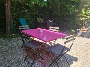a pink picnic table with three chairs in a yard at Tiny Isle in L'Isle-sur-la-Sorgue