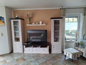 a living room with a television and white cabinets at Mövennest in Berumbur