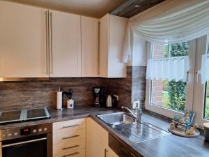 a kitchen with white cabinets and a sink and a window at Mövennest in Berumbur