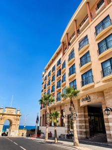 a large building with palm trees in front of it at Vivaldi Hotel in St. Julianʼs