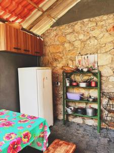 a kitchen with a refrigerator and a shelf with pots and pans at Chalés do quintal da chapada in Palmeiras