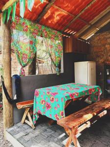 a table and a bench in a room with a table and a refrigerator at Chalés do quintal da chapada in Palmeiras