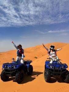 two people riding on atvs in the desert at Sahara Nomadic Luxury Camp in Merzouga +20 photos