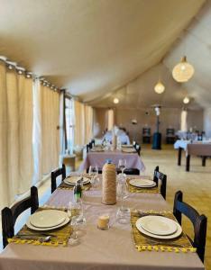 a long table with plates and wine glasses on it at Sahara Nomadic Luxury Camp in Merzouga