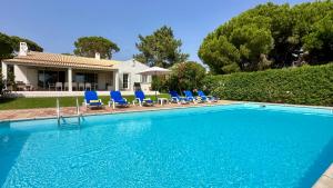 a swimming pool with blue chairs and a house at Sol - Private Pool - 14 Guests - Vilamoura in Vilamoura