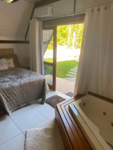 a bedroom with a bed and a bath tub at Chalé do amor, sítio pousada vô Maneca in Timbó