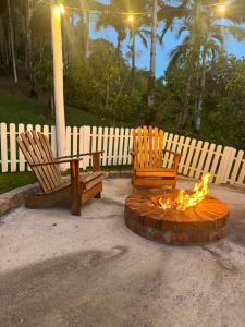 two chairs and a fire pit in front of a fence at Chalé do amor, sítio pousada vô Maneca in Timbó