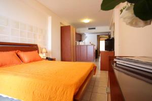 a bedroom with a bed with an orange blanket at Grand Resort nefeli in Vasiliki