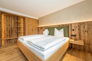 a large bed in a room with wooden walls at Landhaus Lengg in Reit im Winkl