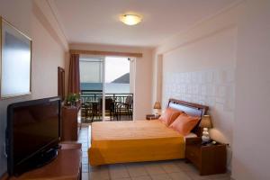 a bedroom with a bed and a flat screen tv at Grand Resort nefeli in Vasiliki
