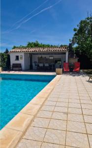a swimming pool with red chairs and a house at Maisonnette et Campagne Provençale, avec Piscine in Orgon