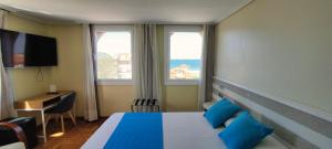 a hotel room with a bed and two windows at Hotel Miramar Playa America Nigran in Nigrán