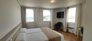 a bedroom with a bed and windows with a view of the ocean at Hotel Miramar Playa America Nigran in Nigrán