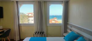 a bedroom with a bed and two windows with the ocean at Hotel Miramar Playa America Nigran in Nigrán