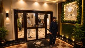 a man is standing in front of a hotel at White Shell Hotel in Karachi