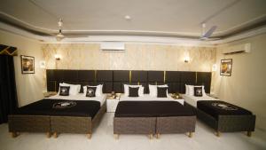 a bedroom with two beds and two ottomans at White Shell Hotel in Karachi