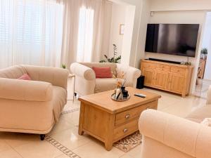 a living room with couches and a flat screen tv at Luxury Villa Aurelia in Peyia