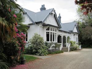 a white house with flowers in front of it at White Elephant Accomodation in Motueka