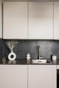 a kitchen with white cabinets and a sink at Diff-Rent Studios with gym & Fast Access to Central London & Wembley in Harrow