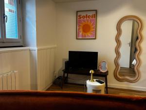 a living room with a television and a mirror at La Parenthèse Meymacoise in Meymac