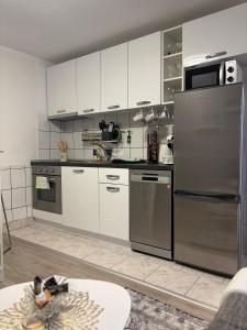 a kitchen with white cabinets and stainless steel appliances at Apartman Indy in Marčelji